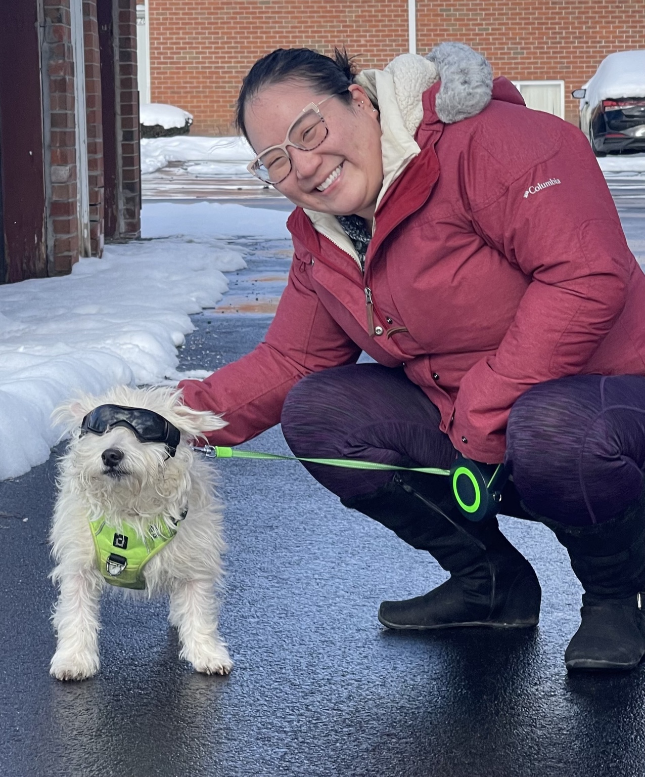 Amy smiling beside a white dog outdoors